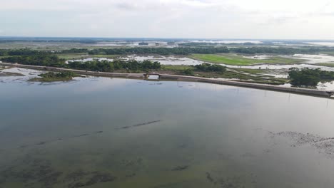 Aerial-shot-overhead-flooded-farmland-with-a-road-running-through-the-countryside