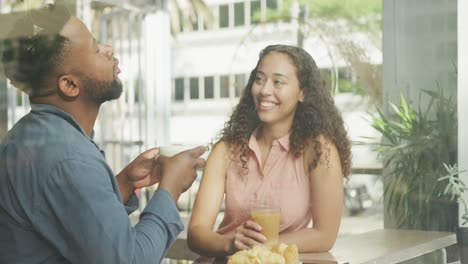 happy diverse couple spending time together at cafe, drinking coffee and talking