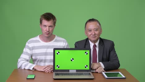 mature japanese businessman and young scandinavian businessman working together