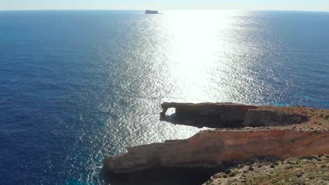 Drone-shot-over-rocks-in-nature-and-towards-a-natural-stone-window-on-the-Mediterranean-sea-of-Malta-5