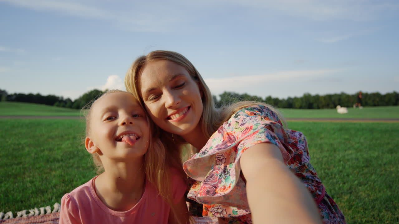 familia feliz divirtiéndose en el prado. mujer y niña posando para la cámara al aire libre.