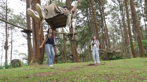 indonesian friends playing on a swing in forest during outdoor travel adventure