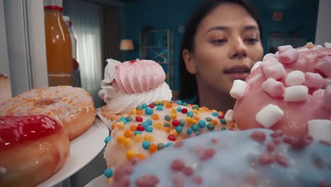 woman reaching for donuts and cupcakes in a refrigerator