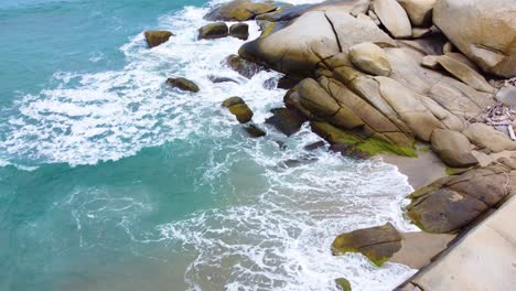 Calm-blue-ocean-waves-breaking-against-the-rocks-on-a-beach-shoreline