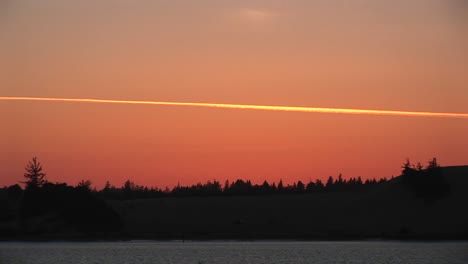 el tiro largo de la estela de vapor de un avión hace una raya colorida en el cielo de la hora dorada