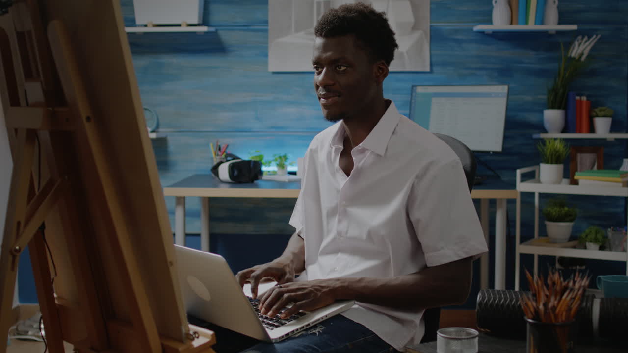 Artist of african american ethnicity using laptop computer