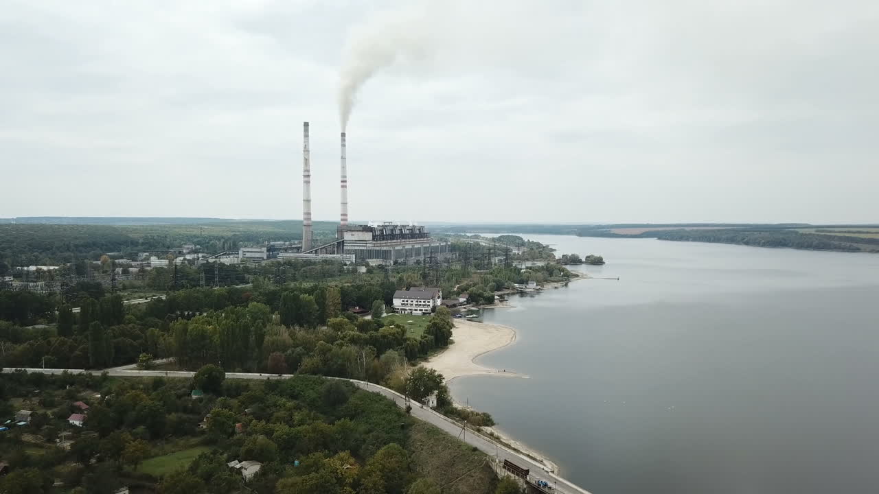 Aerial view of coal power station with smoke goes from tubes. Fog or clouds cover the land. View from the birds-eye view.