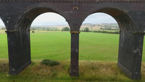 aerial drone cinematic footage of railway viaduct with multiple arches crossing farmland and wetlands harringworth near corby england uk