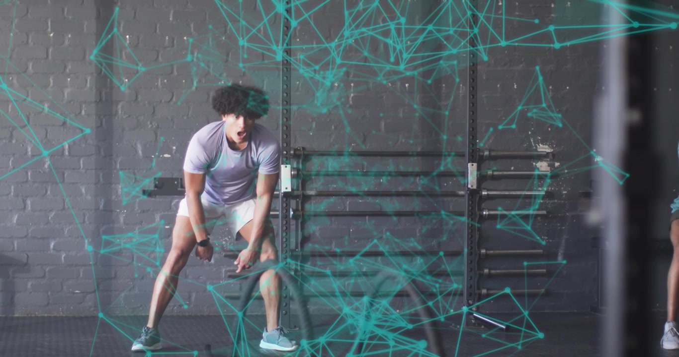 Adult male grabbing battle ropes, performing waves for gym strength as partner stepping in