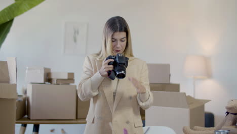 young female entrepreneur in elegant jacket taking photo of products