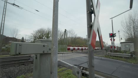 high-speed train passes through a rural railway crossing on a cloudy day
