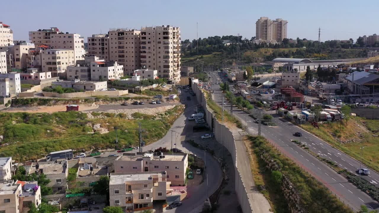 Aerial view of a security barrier and highway separating urban areas