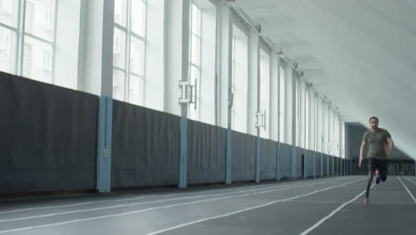 male athlete with prosthetic leg running in stadium