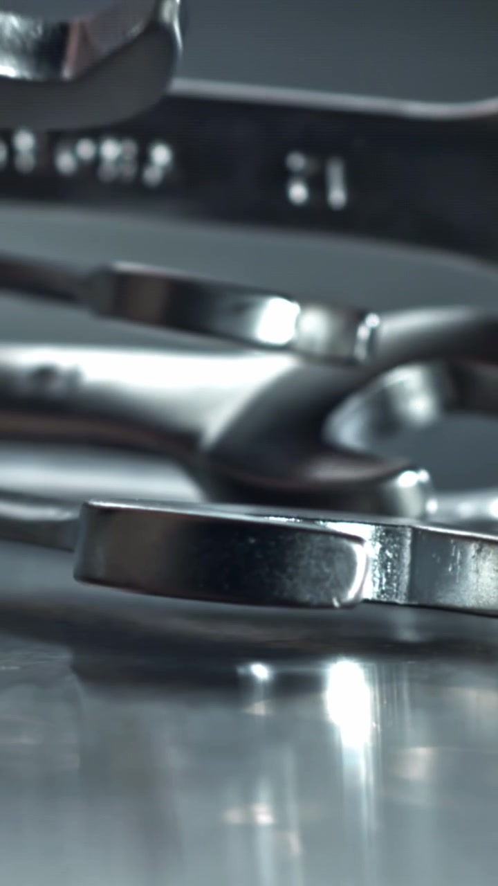 Metallic Wrenches Being Placed on a Reflective Surface in Slow Motion