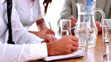 personas de negocios tomando notas en una reunión