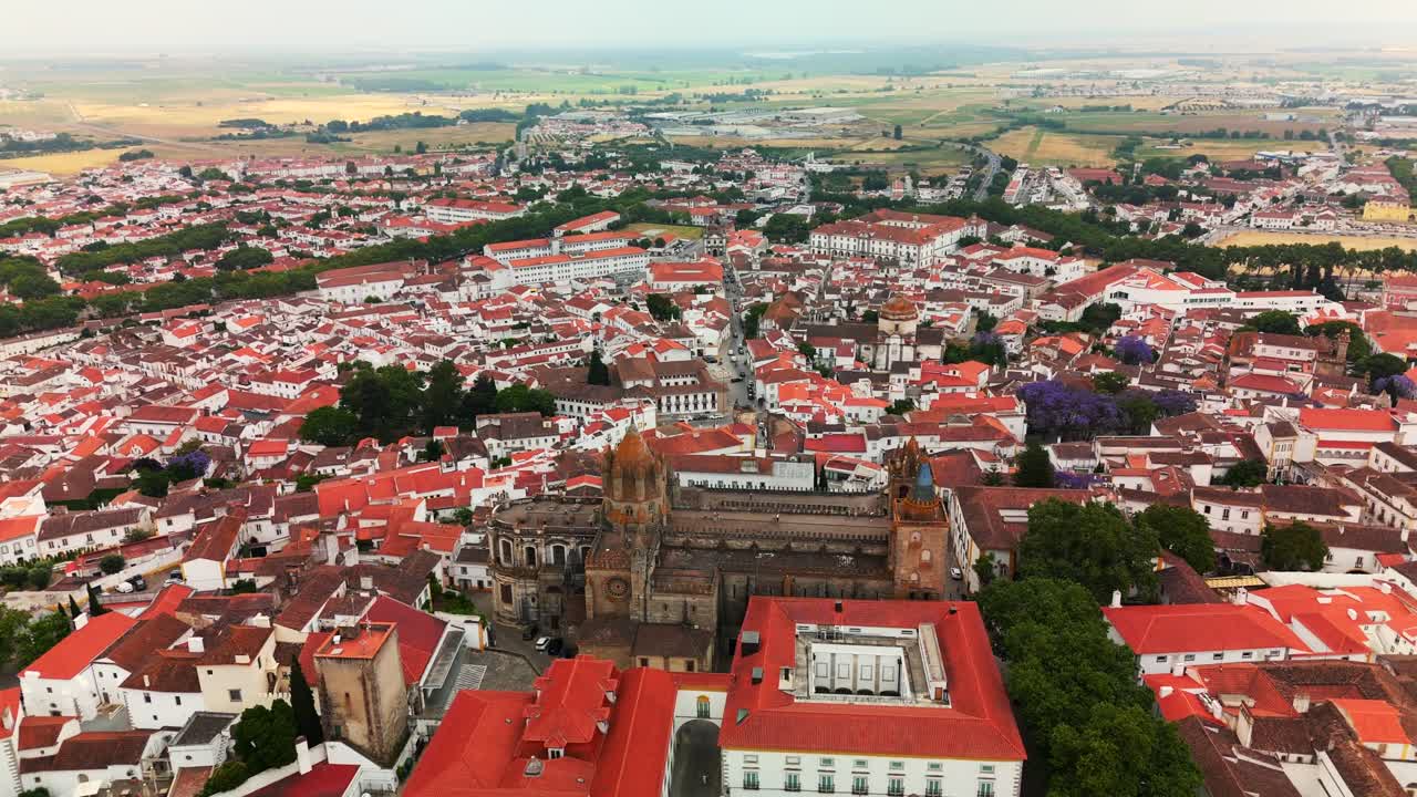 Aerial orbit left circles Évora Cathedral above red rooftops of the historic center