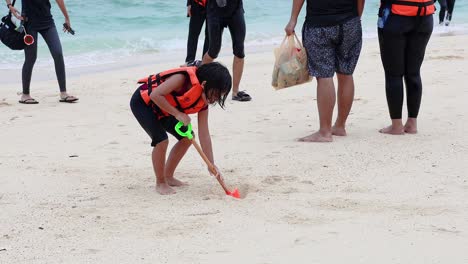 a child digs in the sand with a shovel