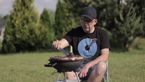 a middle-aged man is barbecuing in the garden during the summer in europe