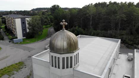 cúpula de cúpula dorada y cruz adornada en la parte superior del techo de la iglesia en la comunidad residencial y el vecindario con árboles verdes escénicos en el día del cielo azul nublado, antena circular