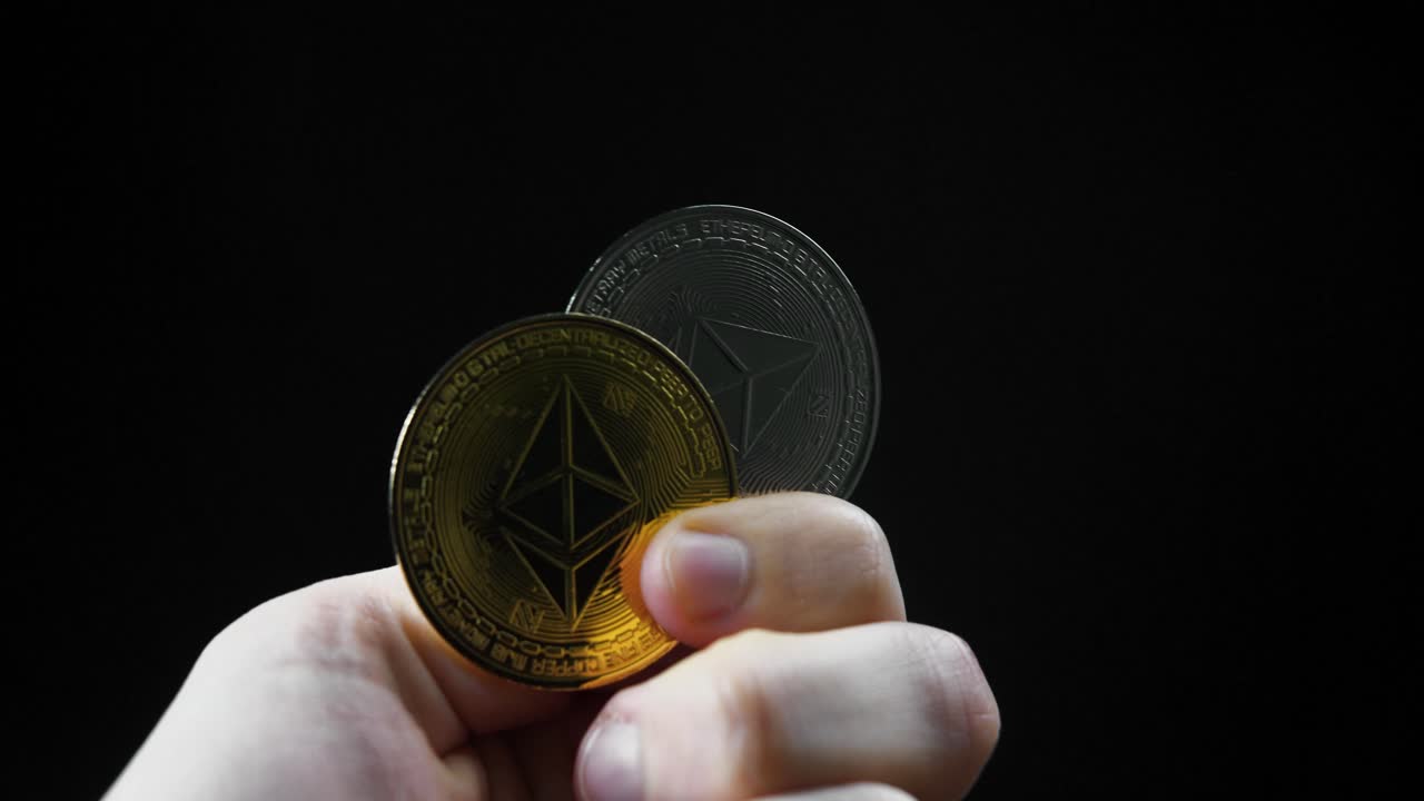 Showing to camera golden and silver Ethereum coins. Close up