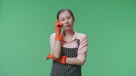 mujer con delantal y guantes, profundamente en pensamiento