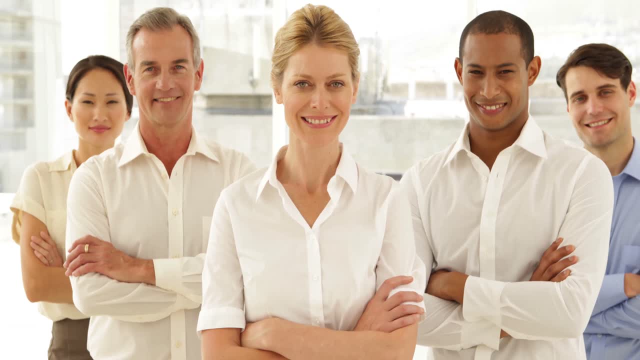 mujer de negocios sonriendo a la cámara con el personal detrás de ella