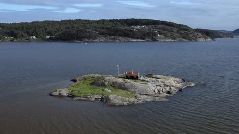 small cabin with flagpole on rocky island surrounded by water on the swedish west-coast during mid-day in summer