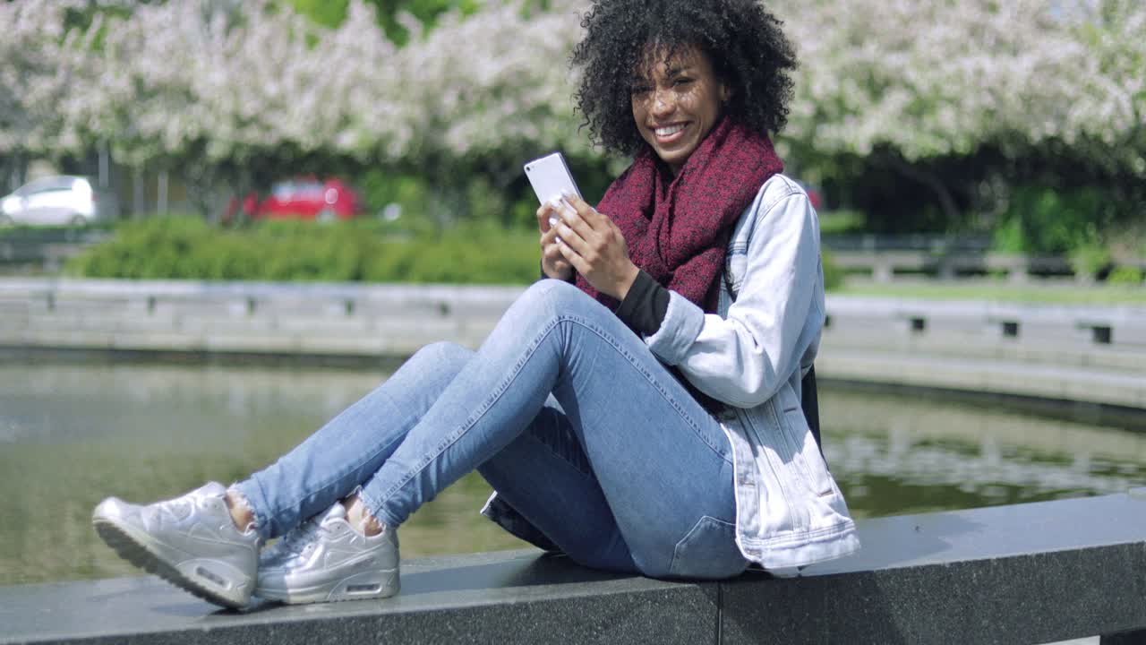 Cheerful woman with smartphone outside