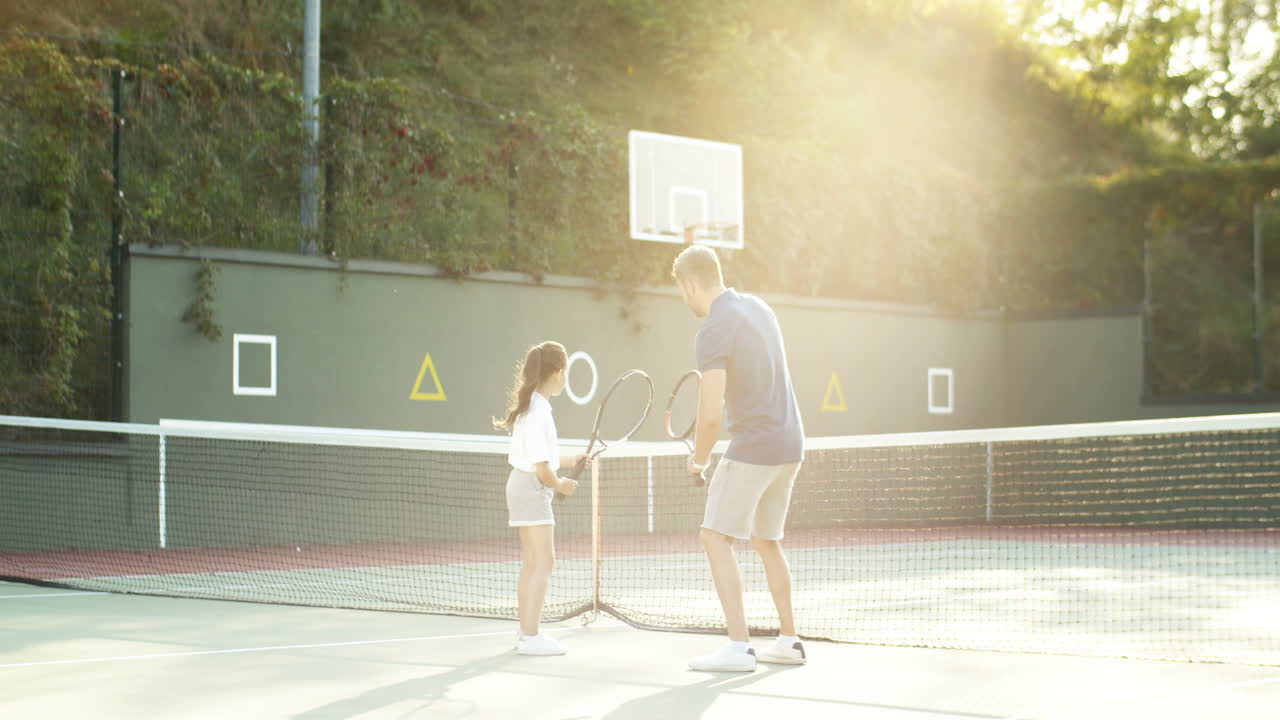 hombre enseñando a su pequeña hija a jugar tenis en un día de verano 2