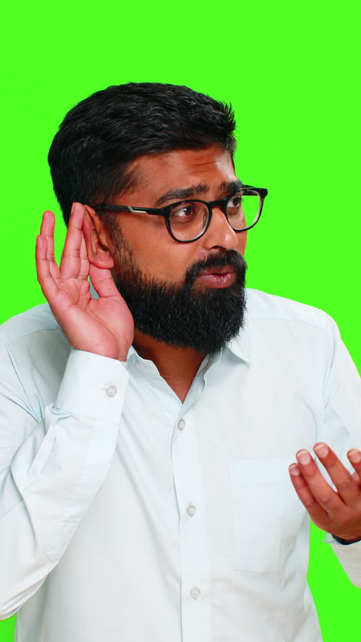 Indian man frowning and holding hand to ear pretending not to hear showing confusion surprise