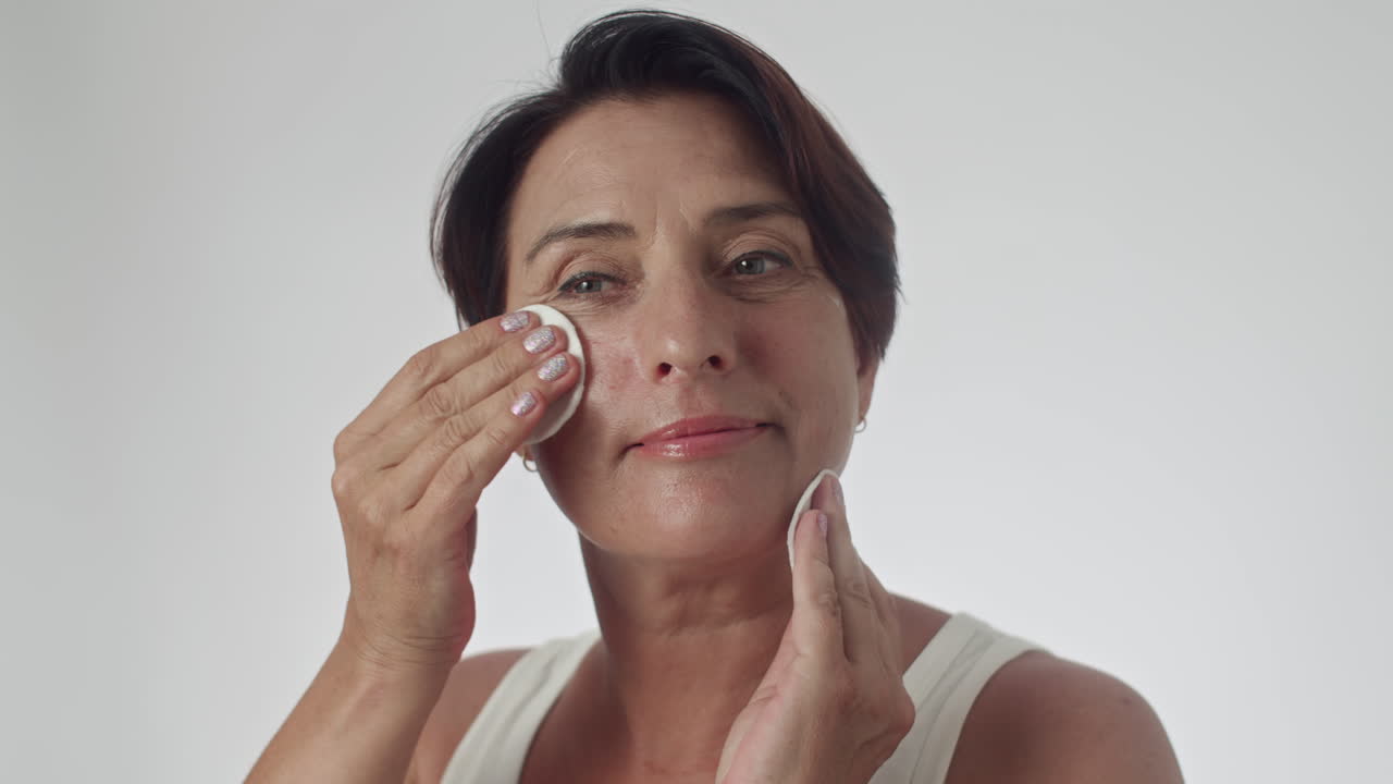 Middle-aged Woman Cleansing Skin on Face with Cotton Pads