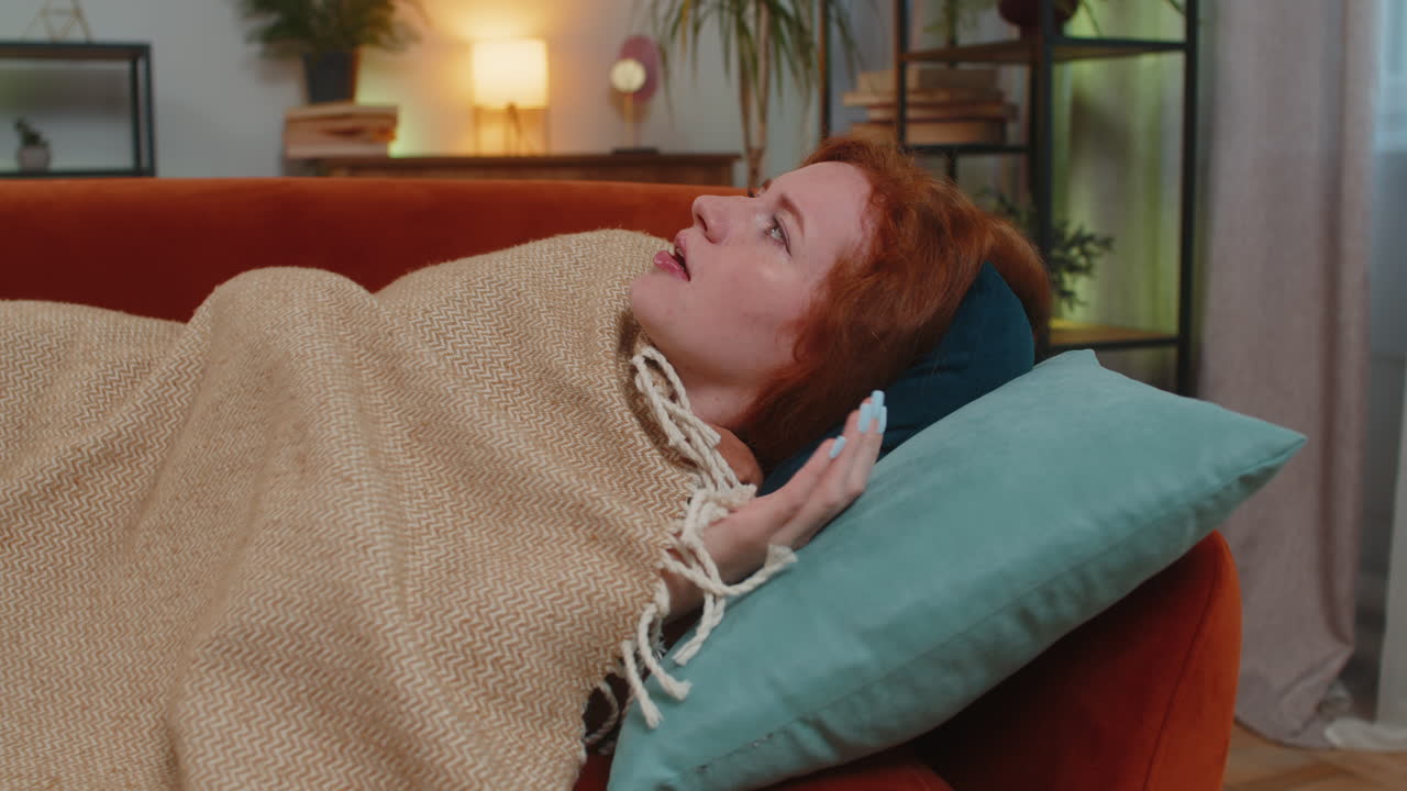 여성은 불안 장애로 인해 소파에서 잠을 자면서 갑자기 악몽에서 깨어납니다.