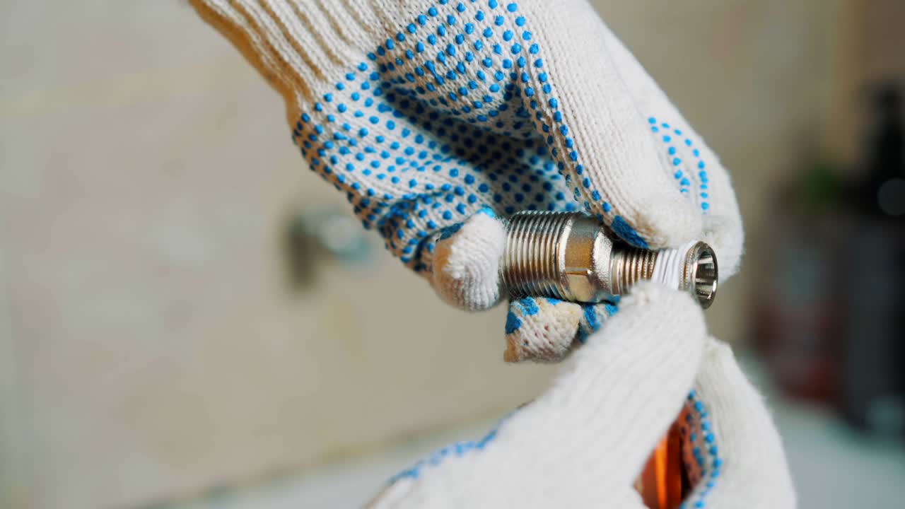 cerca de un hombre está sellando cinta de envoltura alrededor del tornillo del grifo de agua de hierro