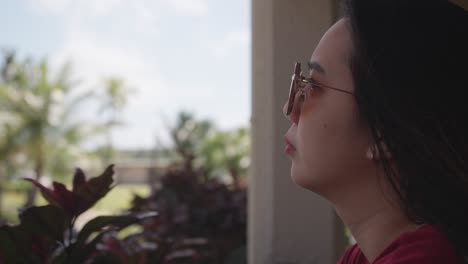 Close-up-shot-of-a-girl-relaxing-at-her-front-porch-while-holding-a-phone-during-a-windy-morning