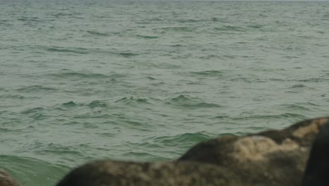 Slow-motion-of-rippling-sea-water-with-rocks-in-foreground