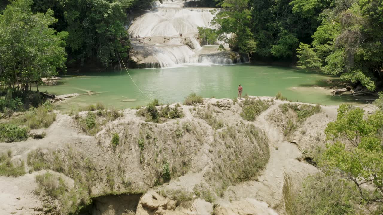 la antena se inclina hacia arriba mostrando a una mujer caminando junto a las cascadas de roberto barrio en palenque, chiapas, méxico