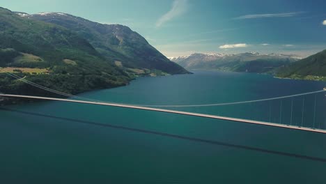 panning reveal drone shot of a suspension bridge on a sunny day