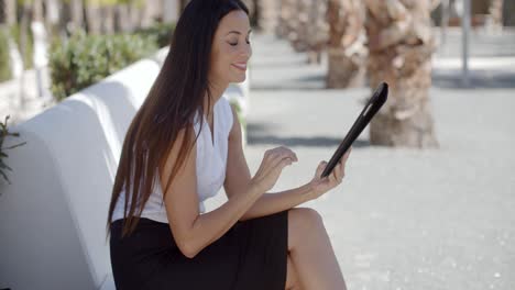 Smiling-young-woman-using-her-tablet-outdoors