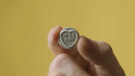 노란색 배경에 당신이 그리워요 메시지와 함께 심장 사탕을 들고 손을 닫습니다