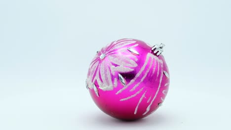 christmas pink ball with silver glittered flower rotating on white background.