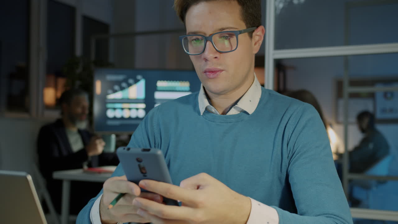 Businessman working on his smartphone at night in an office