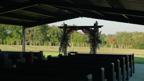a cinematic gimbal shot moving toward a beautifully decorated ceremony arch with a vineyard in the background, capturing the serene wedding setting.