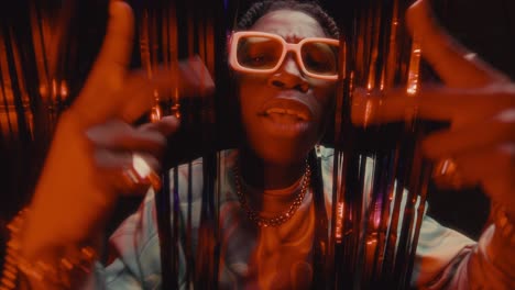 black rapper giving performance against shimmering tinsel curtains