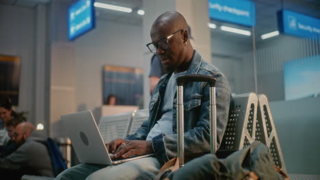 hombre trabajando en una computadora portátil en la sala de espera del aeropuerto
