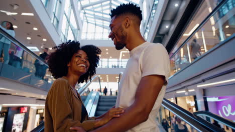 happy black couple on escalator in shopping mall