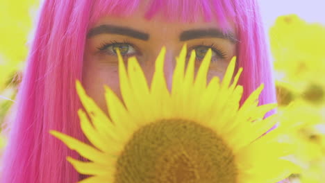 una chica feliz con cabello rosa y ojos brillantes sostiene un girasol en esta cámara lenta de cerca