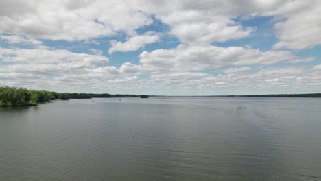 Beautiful-drone-shot-of-Dramatic-sky-above-the-blue-lake-and-island-with-green-birch-trees