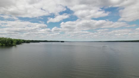 beautiful drone shot of dramatic sky above the blue lake and island with green birch trees