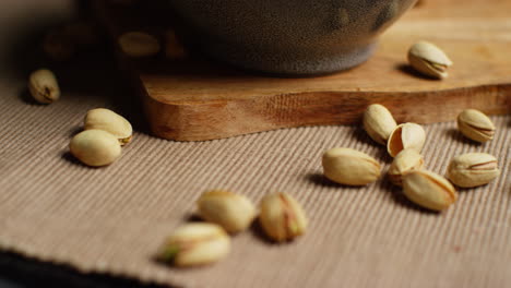 close up shot of pistachio nuts in shells revolving next to bowl