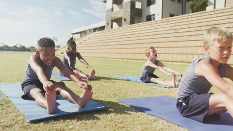 video de niños diversos enfocados practicando yoga en esteras en un día soleado